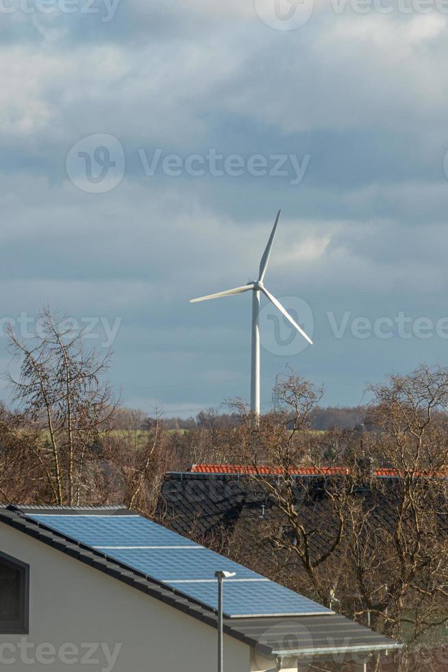 vue plus de magnifique ferme paysage avec de bonne heure printemps agriculture champ, vent turbines à produire vert énergie et une solaire panneaux à le maison toit dans mittweida, Allemagne, à bleu ensoleillé ciel photo