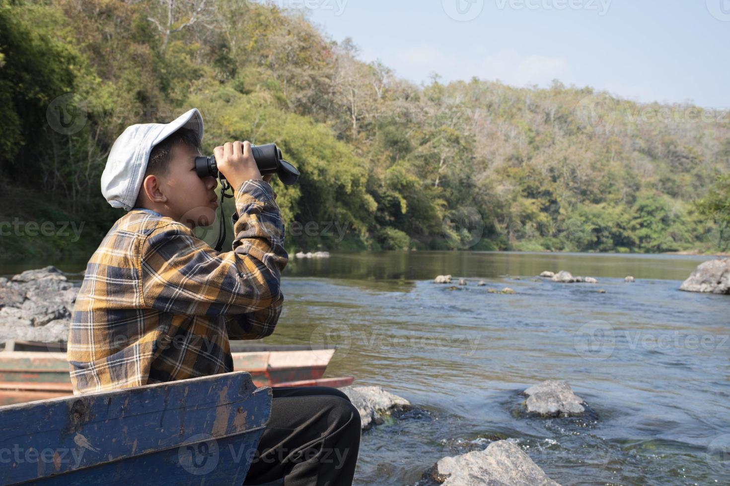 asiatique garçons en utilisant jumelles à faire le observation des oiseaux dans tropical forêt pendant été camp, idée pour apprentissage créatures, faune animaux et insectes à l'extérieur le Salle de classe. photo