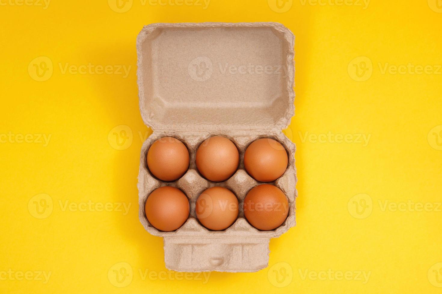 poulet des œufs dans une papier carton boîte sur une Jaune Contexte photo