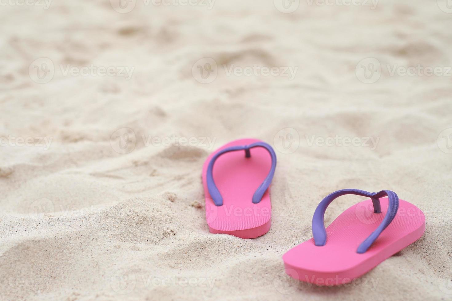 mer sur la plage empreinte de personnes sur le sable et pantoufle de pieds en sandales chaussures sur fond de sable de plage. concept de vacances de voyage. photo
