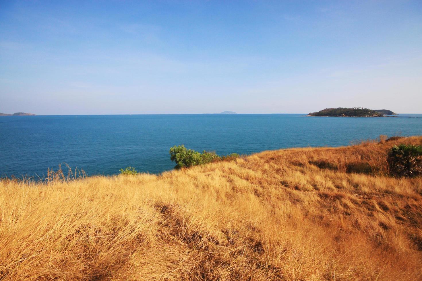 magnifique paysage marin avec ciel crépuscule de le coucher du soleil et mer horizon avec calme et bleu ciel sec herbe champ sur Montagne de phrom thep cap est célèbre endroit dans phuket île, Thaïlande. photo