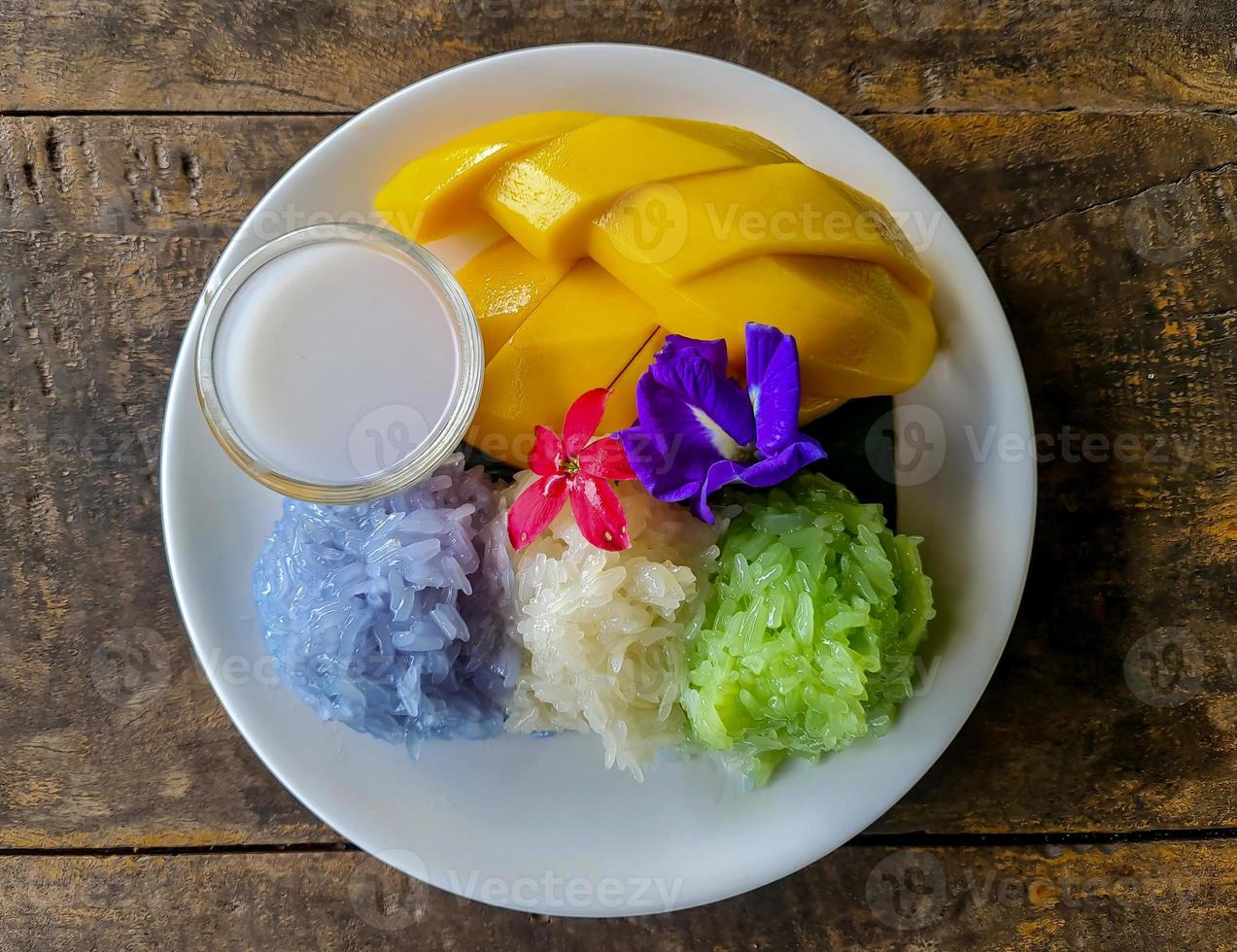 Frais sucré mangue servi avec 3 couleurs gluant riz et noix de coco Lait sur blanc plat. photo