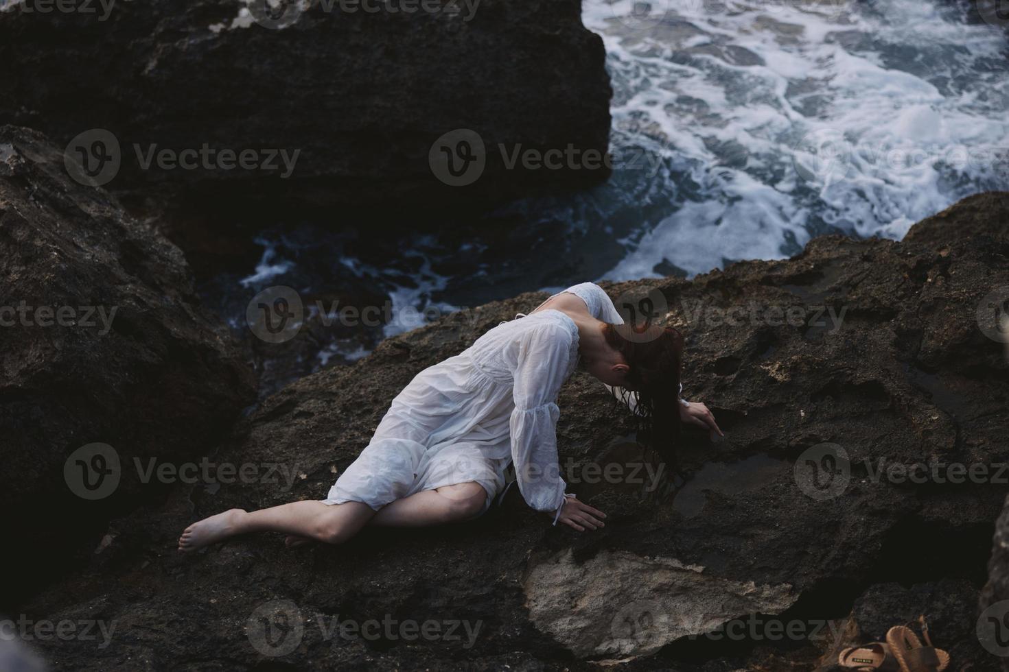 magnifique Jeune femme mensonge sur rocheux côte avec des fissures sur rocheux surface inchangé photo