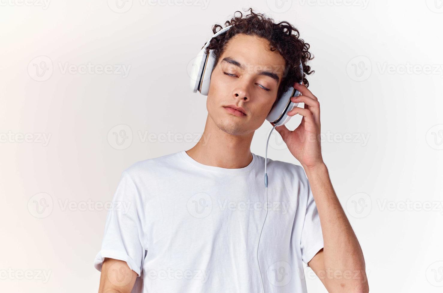 aux cheveux bouclés gars dans blanc T-shirt avec écouteurs la musique La technologie divertissement photo