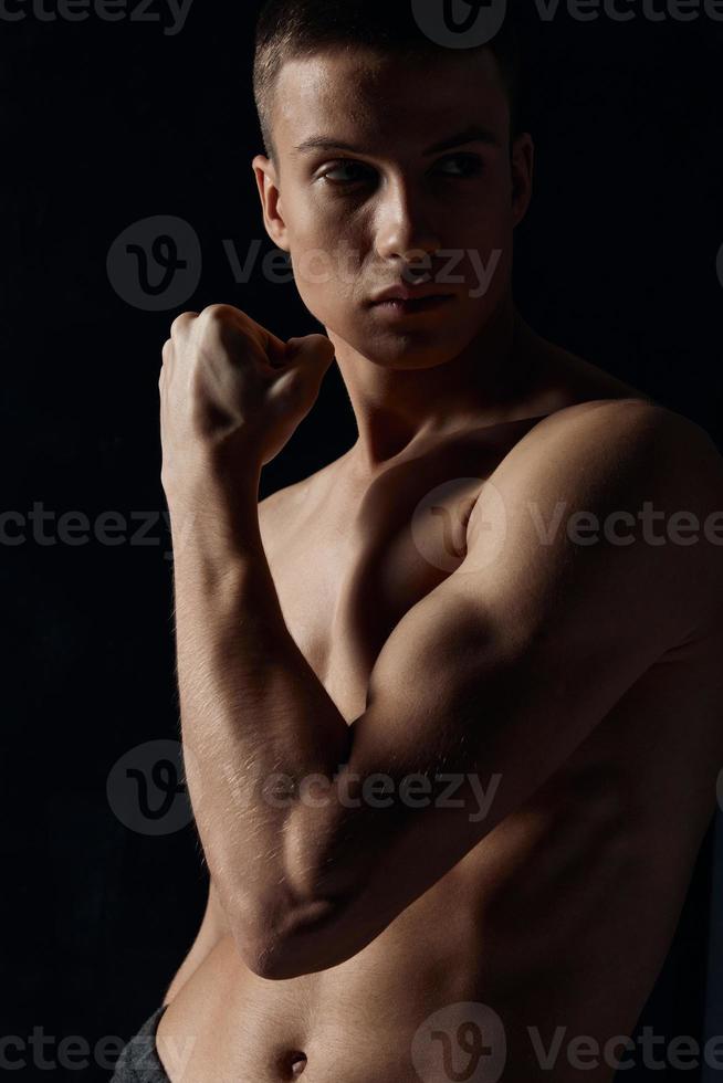 homme avec pompé en haut bras muscles sur une noir Contexte bodybuilder aptitude photo