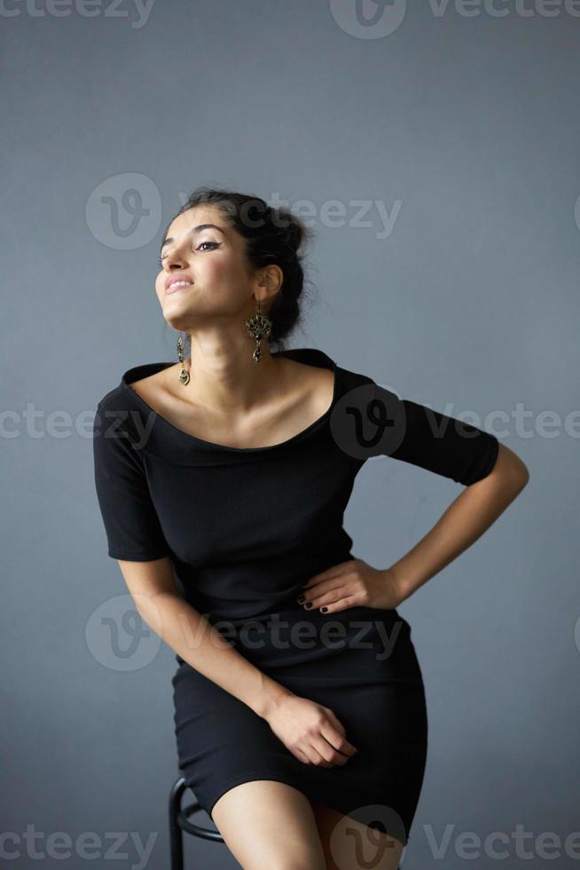 brunette des boucles d'oreilles bijoux posant noir robe mode de vie studio photo