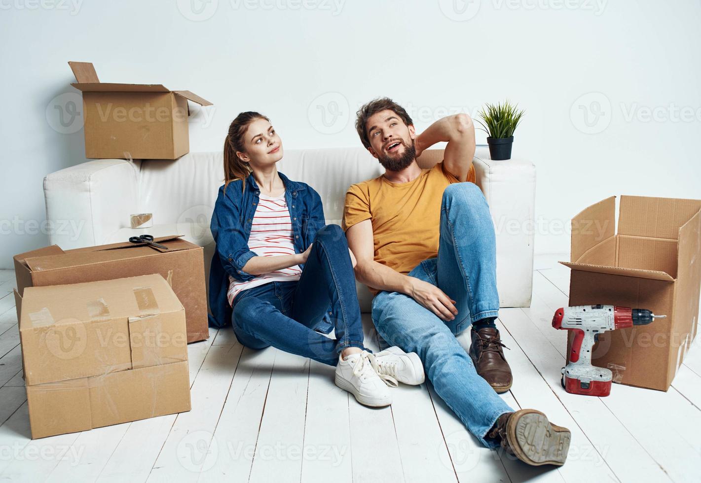 homme et femme sur le planchers dans une Nouveau appartement avec des boites et outils pour réparation photo