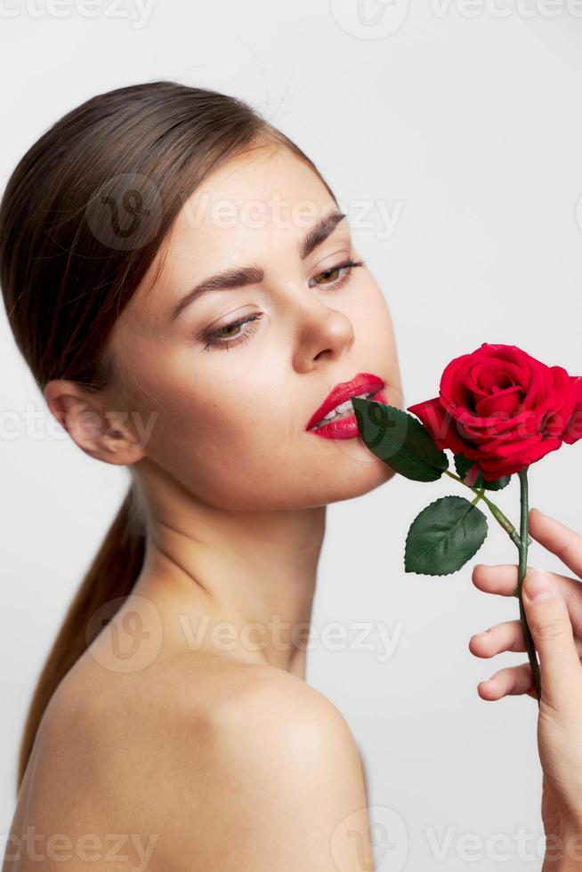 attrayant femme corps détient une Rose près le visage de luxe se soucier photo