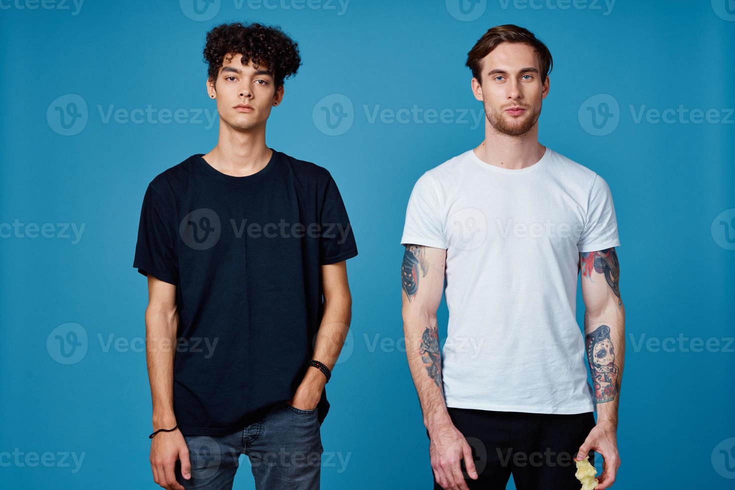 deux Hommes dans t-shirts sur une bleu Contexte et un pantalon bavardage copains photo