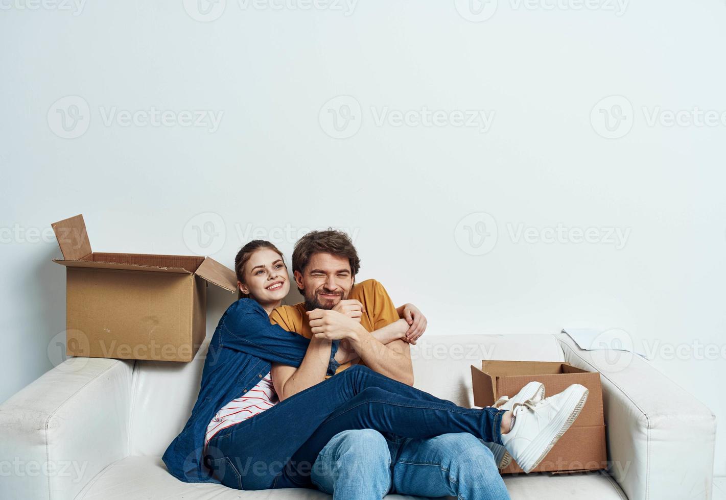 homme et femme séance sur une blanc canapé dans une pièce avec des boites de des choses outils en mouvement photo