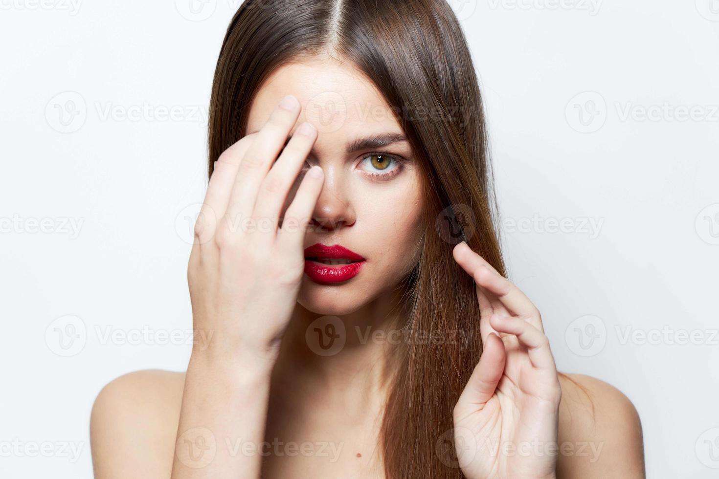 femme avec longue coiffure main près le yeux rouge à lèvres photo