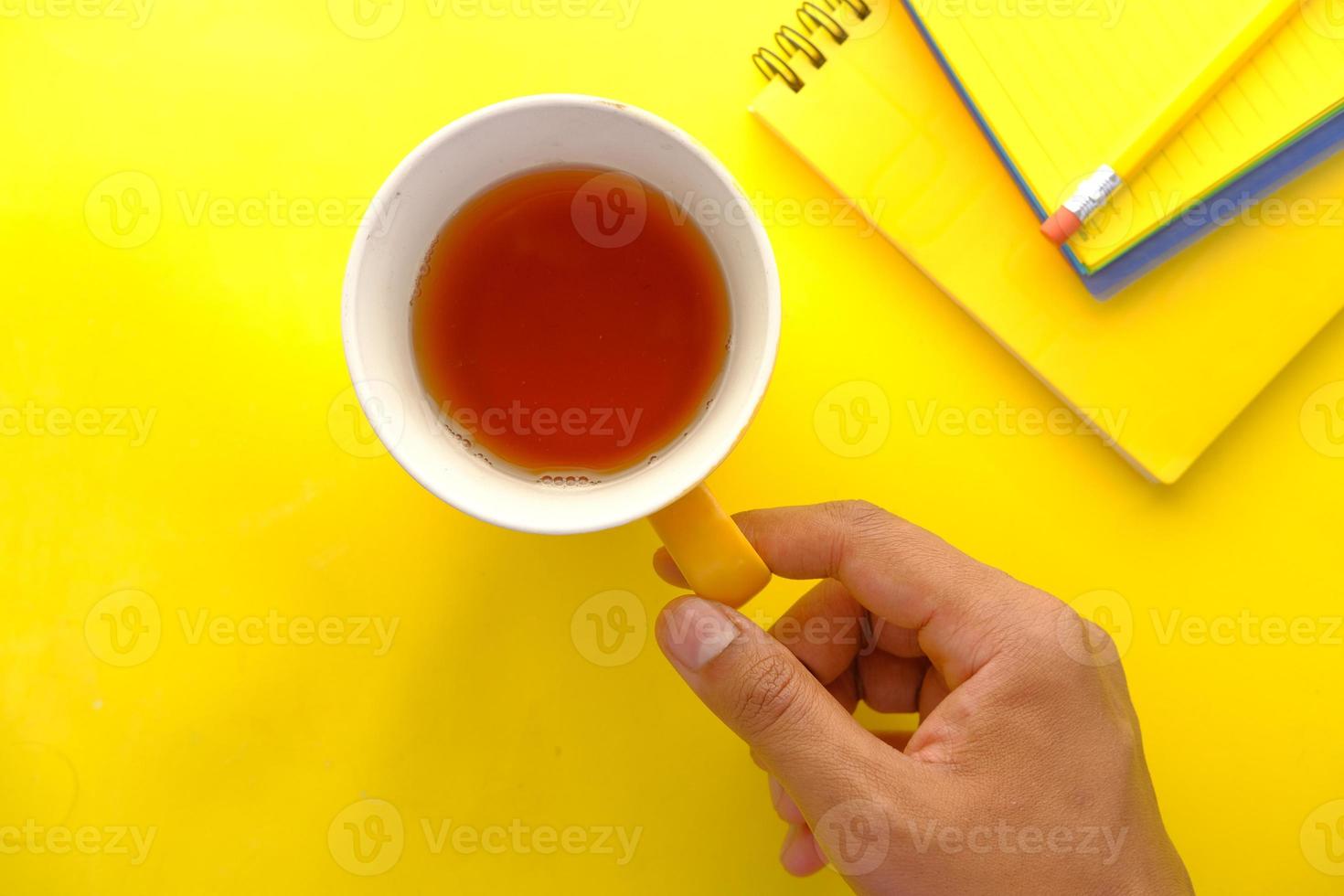 main tenant une tasse de thé vert sur fond jaune photo