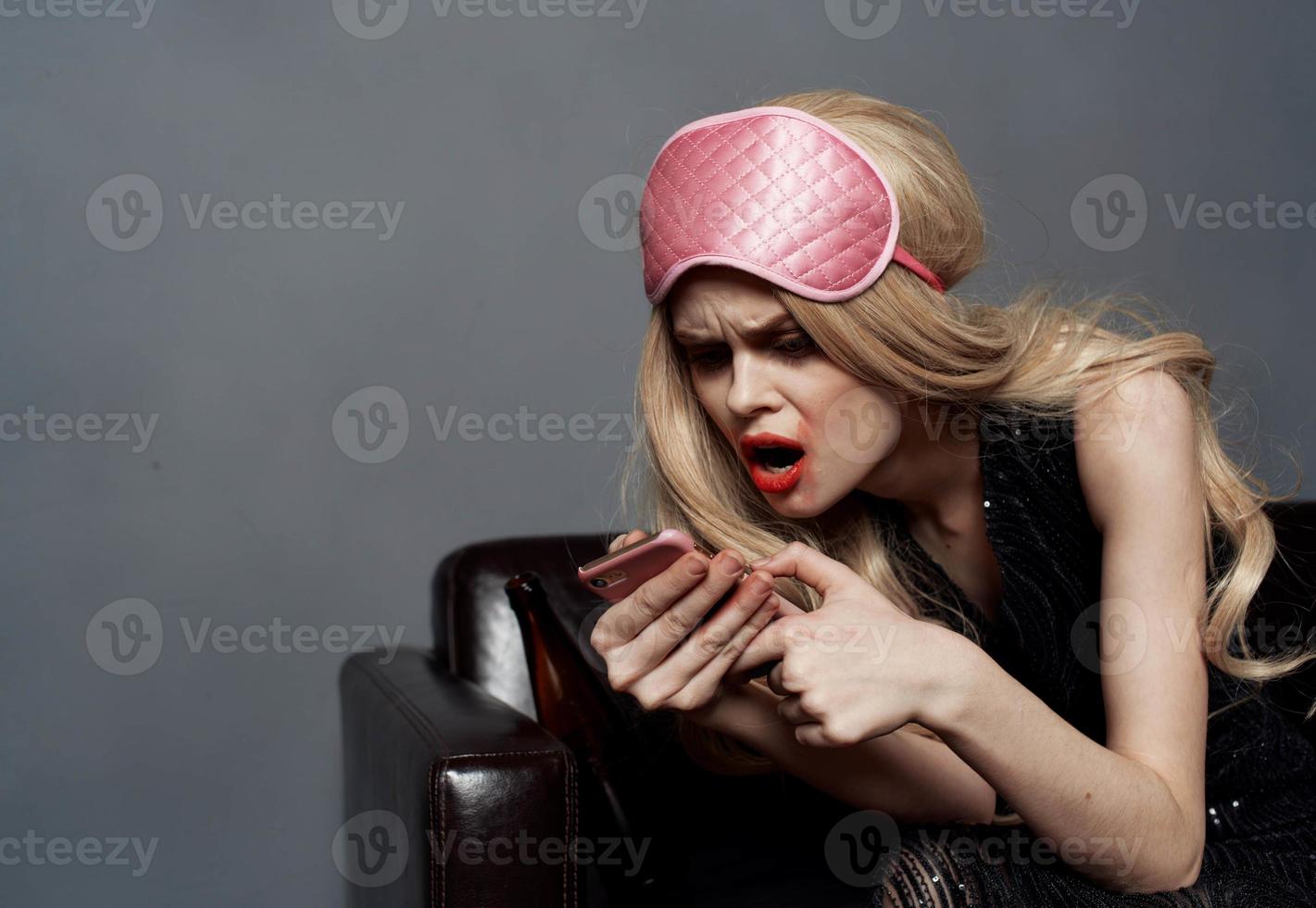 ivre blond femme avec mobile téléphone maquillage et rose sommeil masque photo