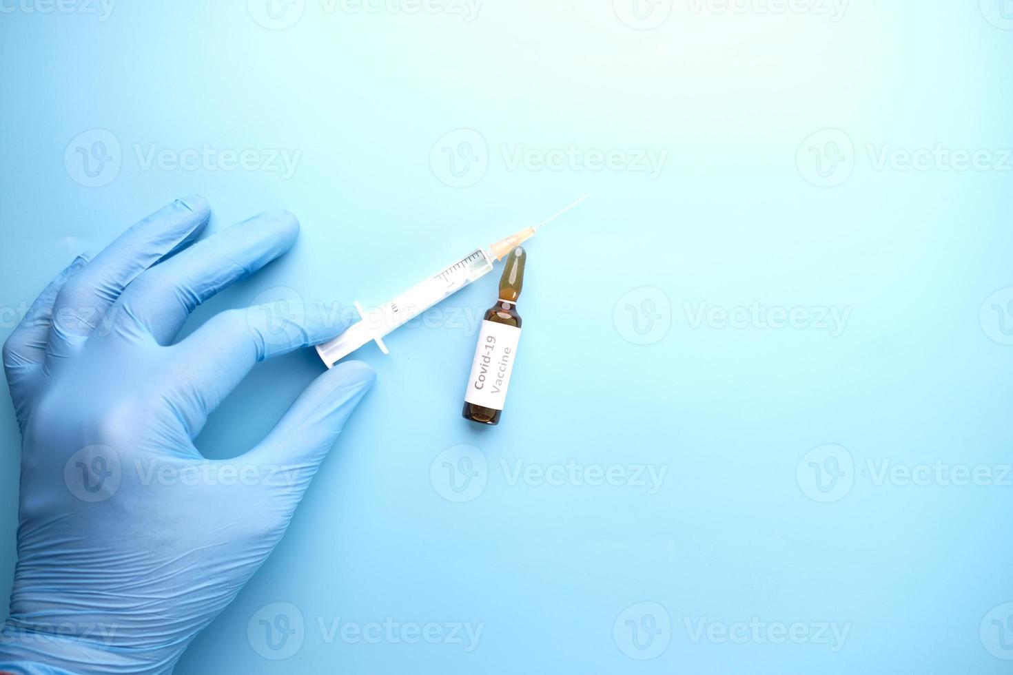 main gantée avec une seringue et le vaccin covid-19 photo