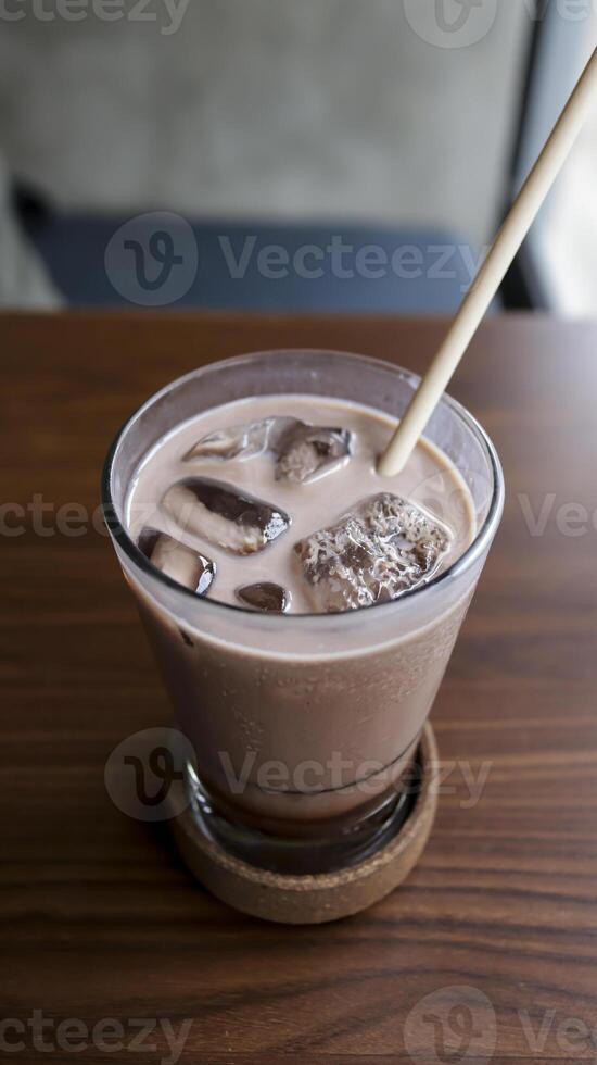 une verre de la glace Chocolat Lait à une table avec une paille. photo