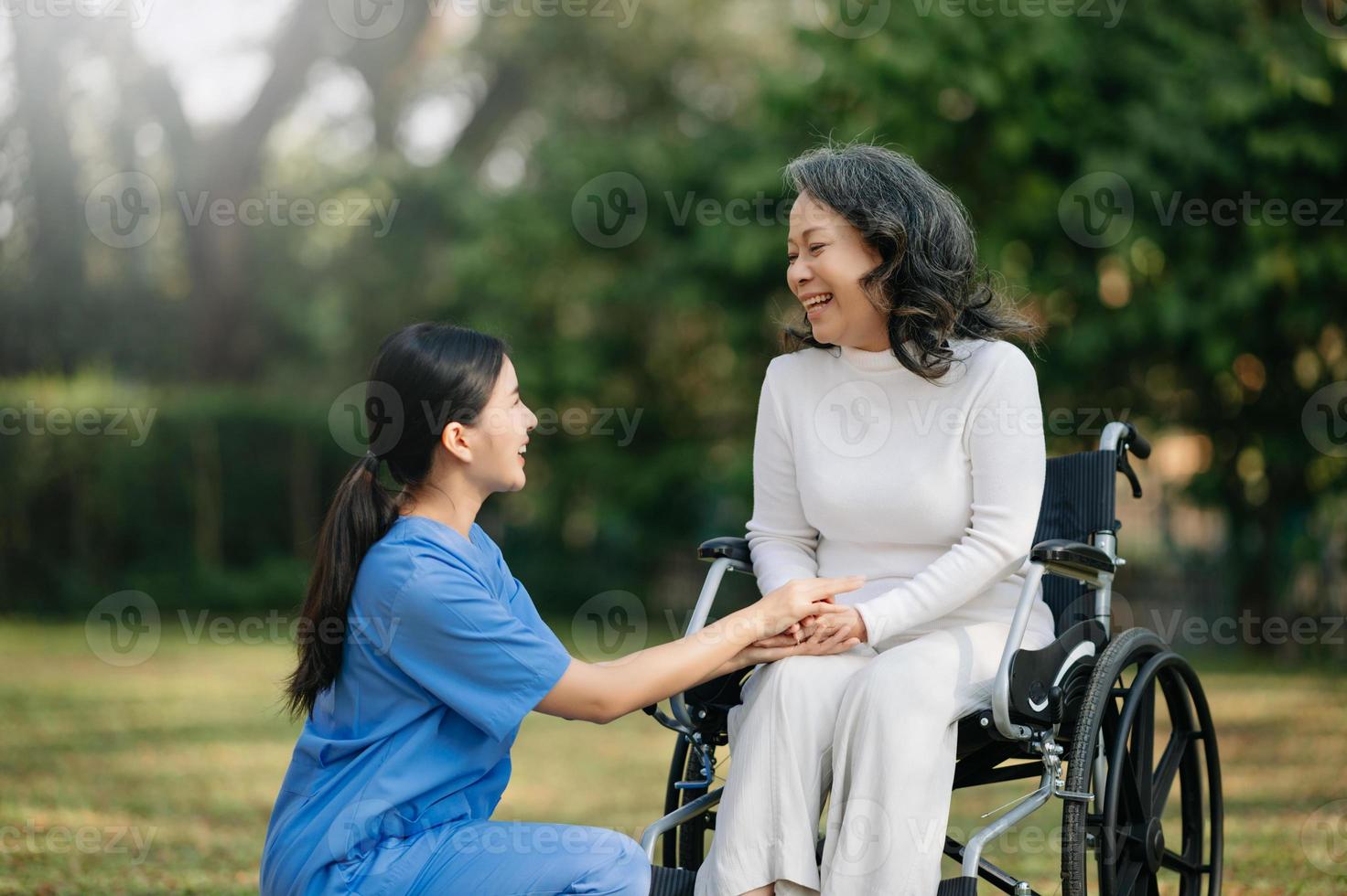 personnes âgées asiatique Sénior femme sur fauteuil roulant avec asiatique prudent soignant. allaitement Accueil hôpital jardin concept. dans Soleil lumière photo