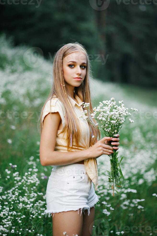 mignonne Jeune femme recueille blanc fleurs sauvages photo