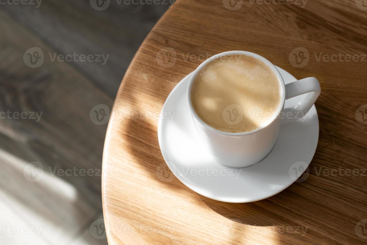 une blanc porcelaine tasse avec café sur une soucoupe des stands sur une rond table photo