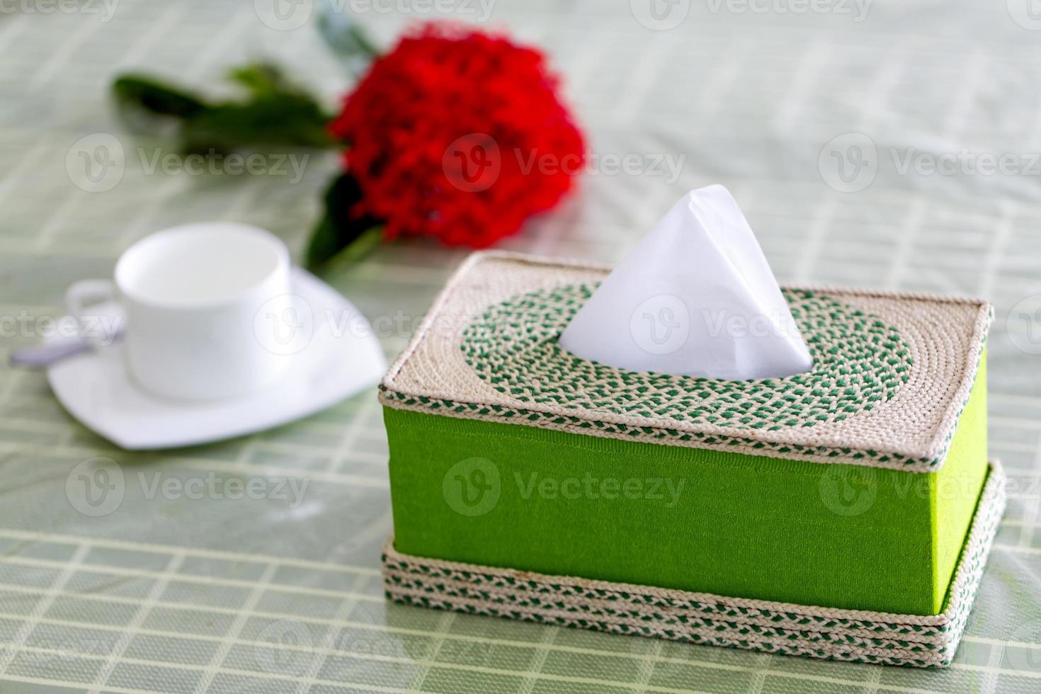 vert Fait main fibre serviette de table boîte sur le à manger table avec une rouge fleur et une blanc tasse à thé. tissu papier boîte sur restaurant. photo