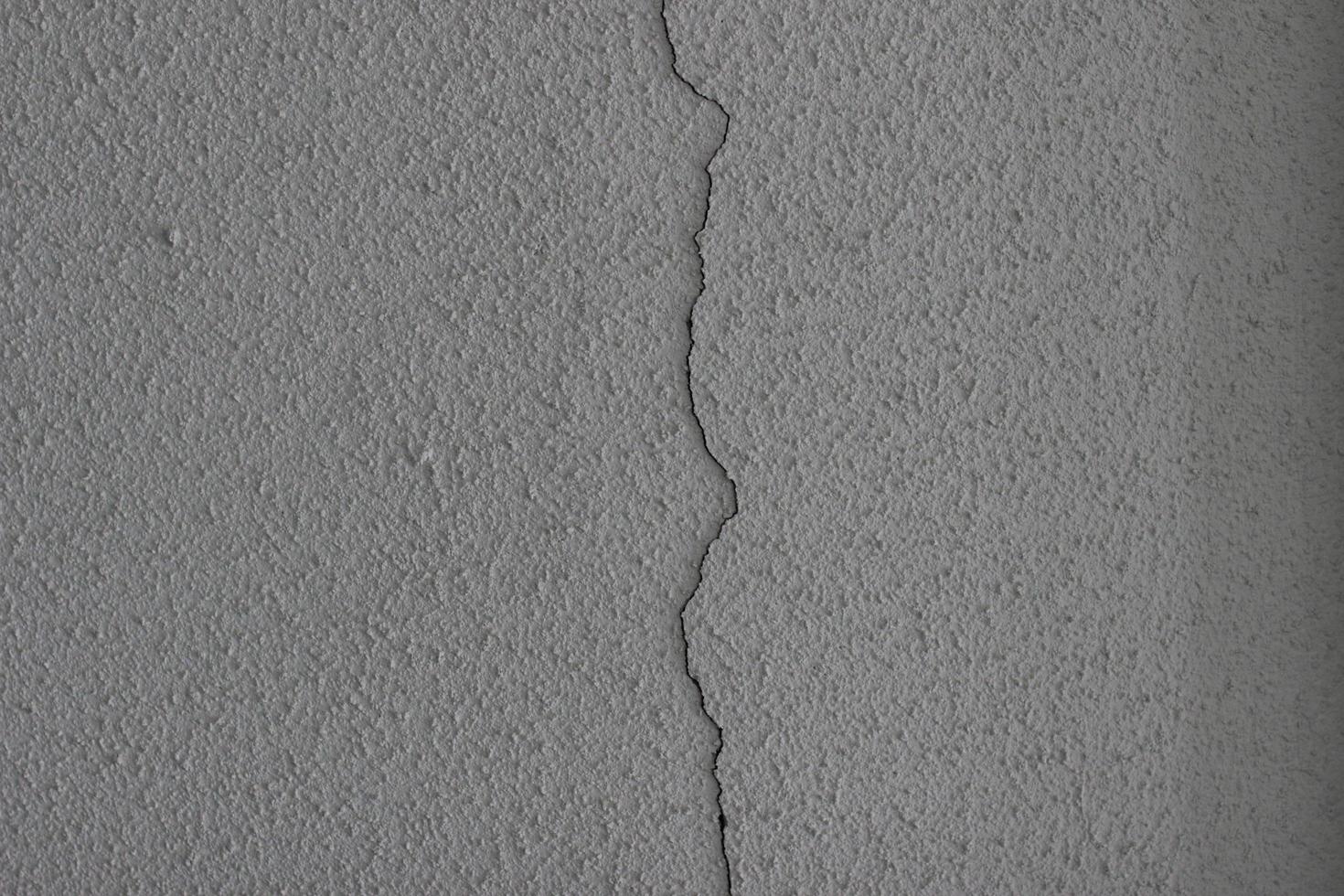 grand verticale fissure dans le blanc mur. plâtre. pauvres construction travail photo