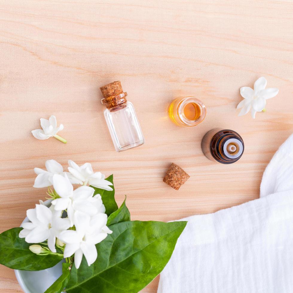 Bouteilles d'huile d'arôme disposées avec des fleurs de jasmin sur fond de bois photo