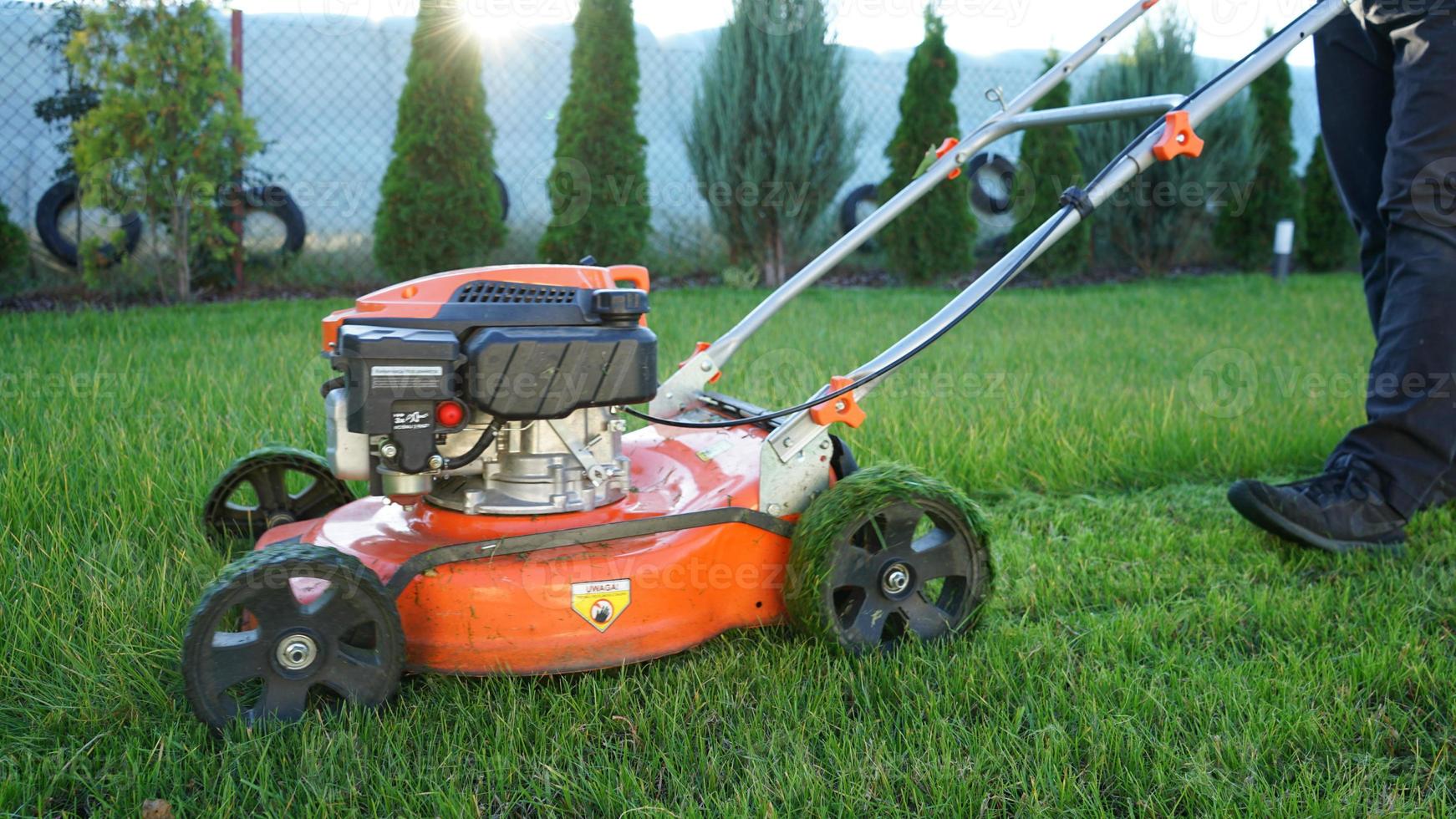 pelouse fauchage. homme Coupe herbe avec le sien Orange pelouse tondeuse. photo