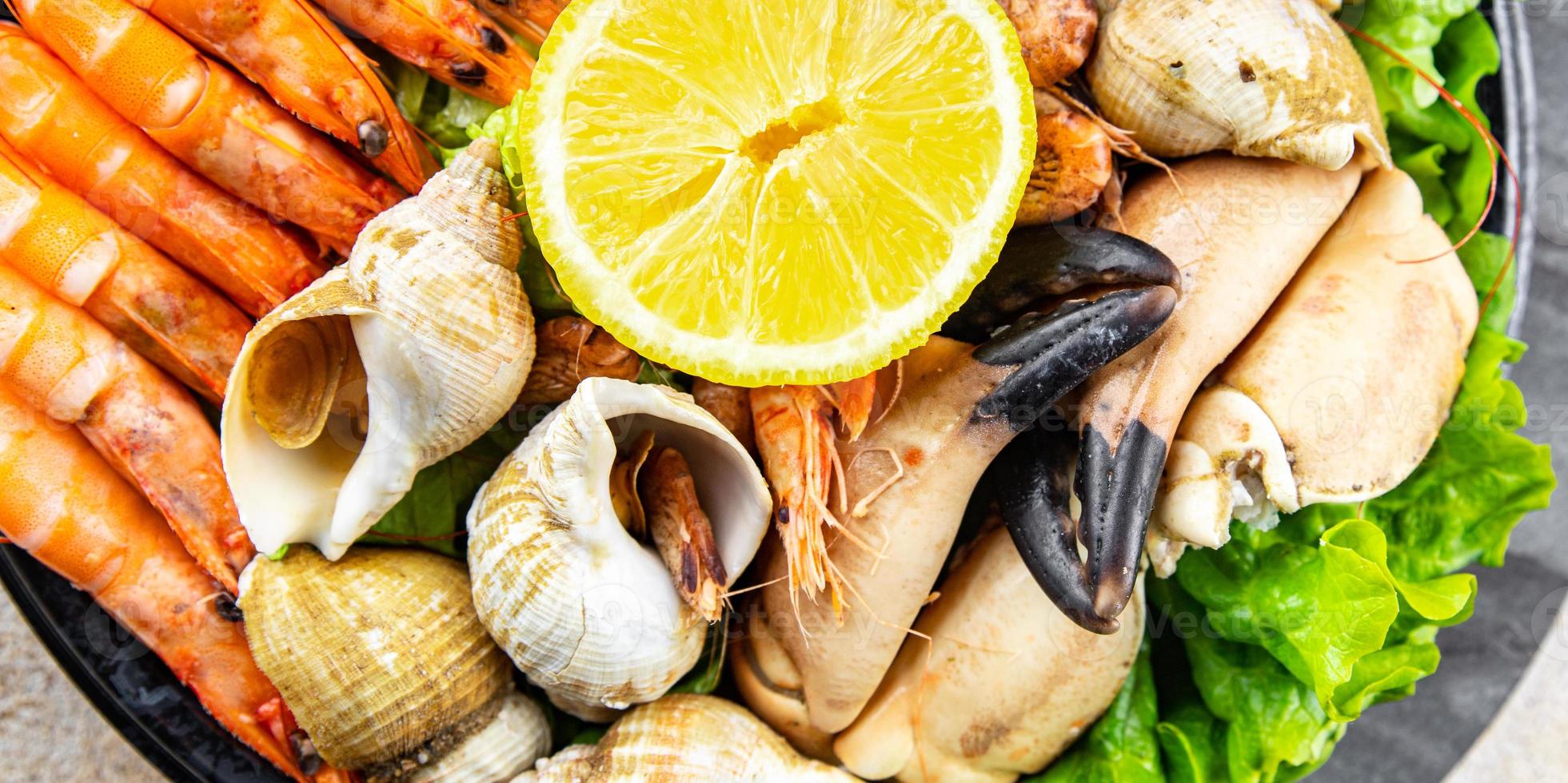 Fruit de mer assiette assorti crevettes, Crabe les griffes, palourdes, rapan, trompette mollusque repas nourriture casse-croûte sur le table copie espace nourriture Contexte rustique Haut vue photo