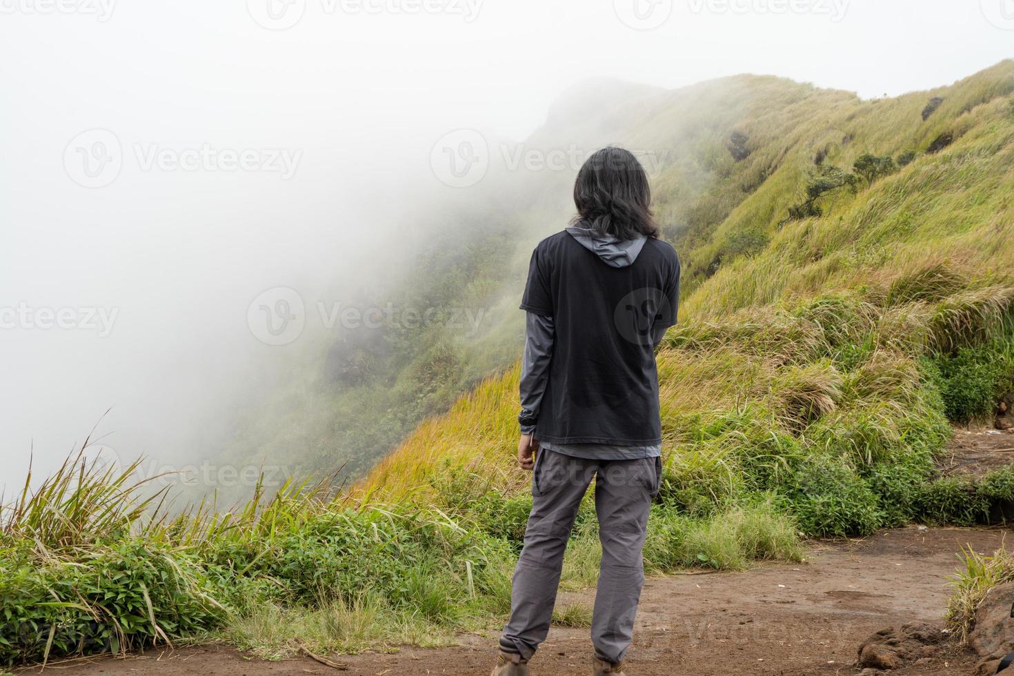 homme randonnée à le Haut montagne, avec savana Piste et nuageux vibrations. le photo est adapté à utilisation pour aventure contenu médias, la nature affiche et forêt Contexte.