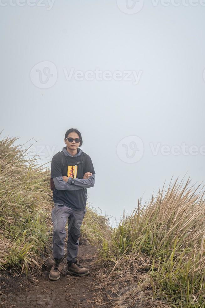 homme randonnée à le Haut montagne, avec savana Piste et nuageux vibrations. le photo est adapté à utilisation pour aventure contenu médias, la nature affiche et forêt Contexte.