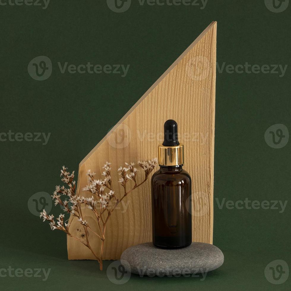 Vue de face de l'arrangement de compte-gouttes de produit de peau sur fond de bois et vert foncé photo