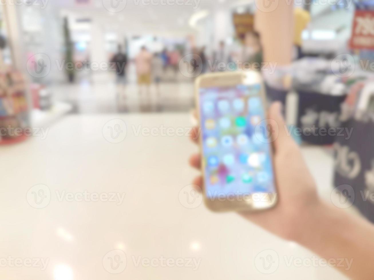 main en portant mobile intelligent téléphone dans achats centre commercial, flou Contexte photo