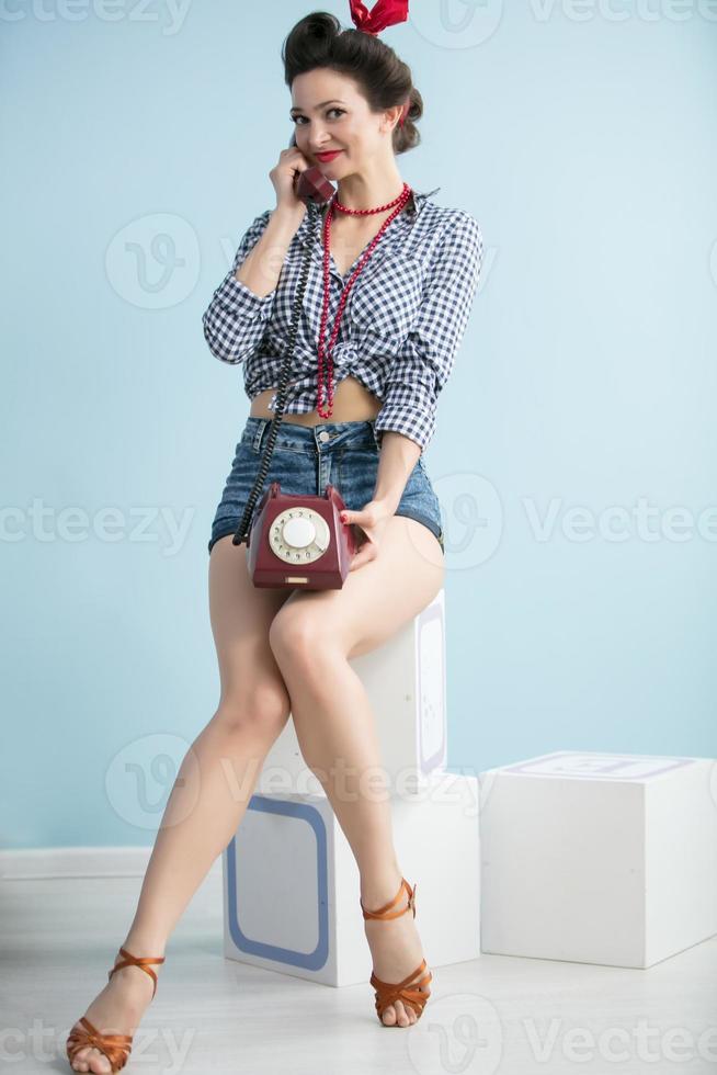 femme dans le style de le la cinquantaine. magnifique rétro femme avec une téléphone sur une bleu Contexte. photo