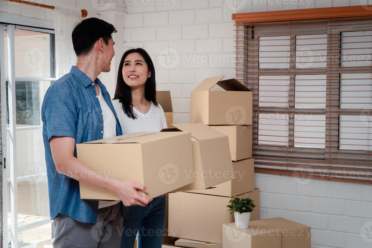 content Jeune couple porter papier carton des boites et en marchant de le de face porte dans le maison dans une Nouveau maison à en mouvement journée. concept de déménagement, de location, et propriétaire en mouvement à maison. photo