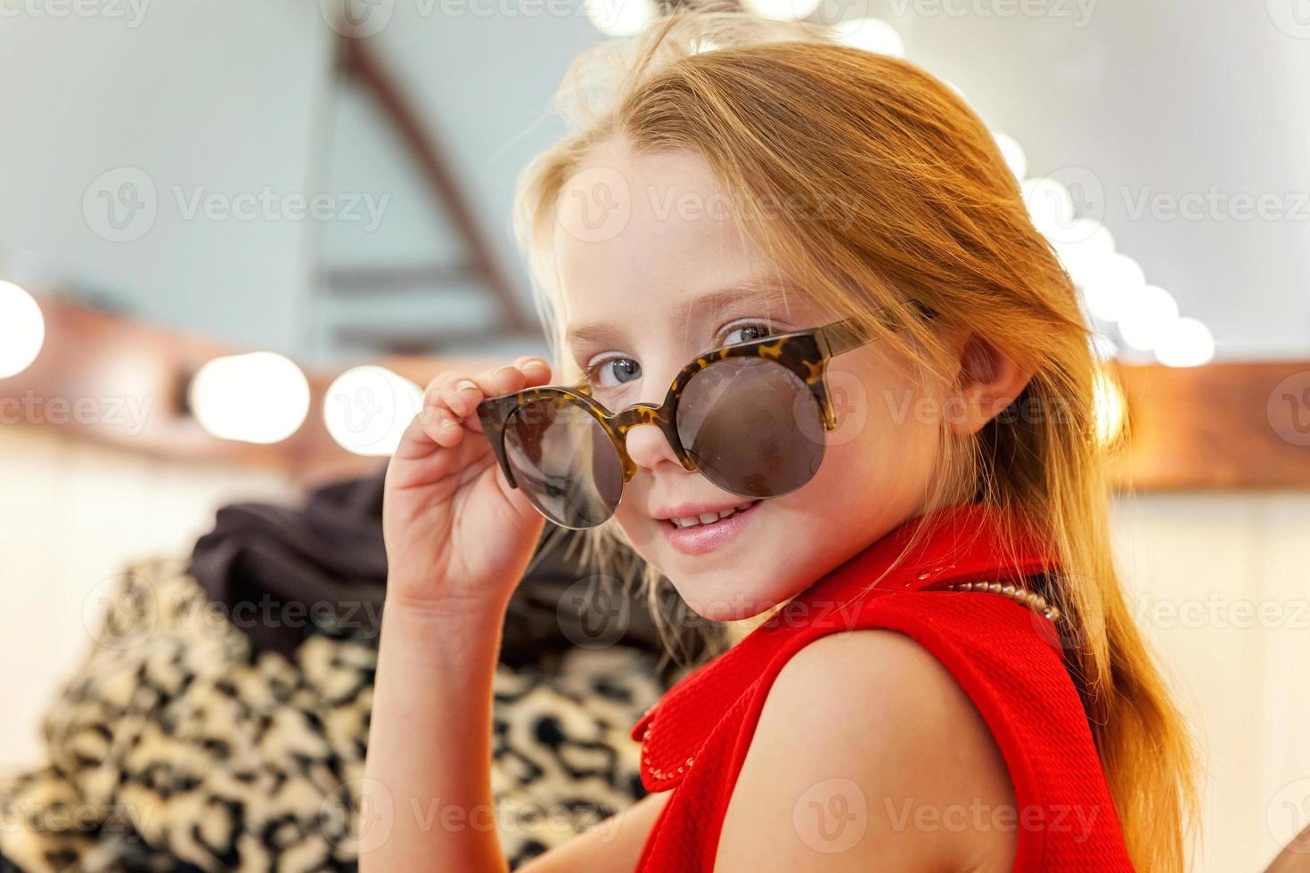 peu fille dans des lunettes de soleil près miroir photo