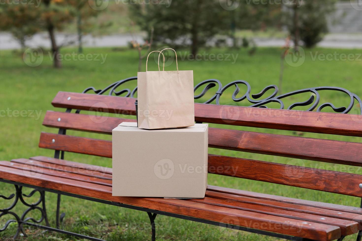 deux colis sur une banc en plein air. sortir concept. en ligne achats. moquer en haut. un service coronavirus photo