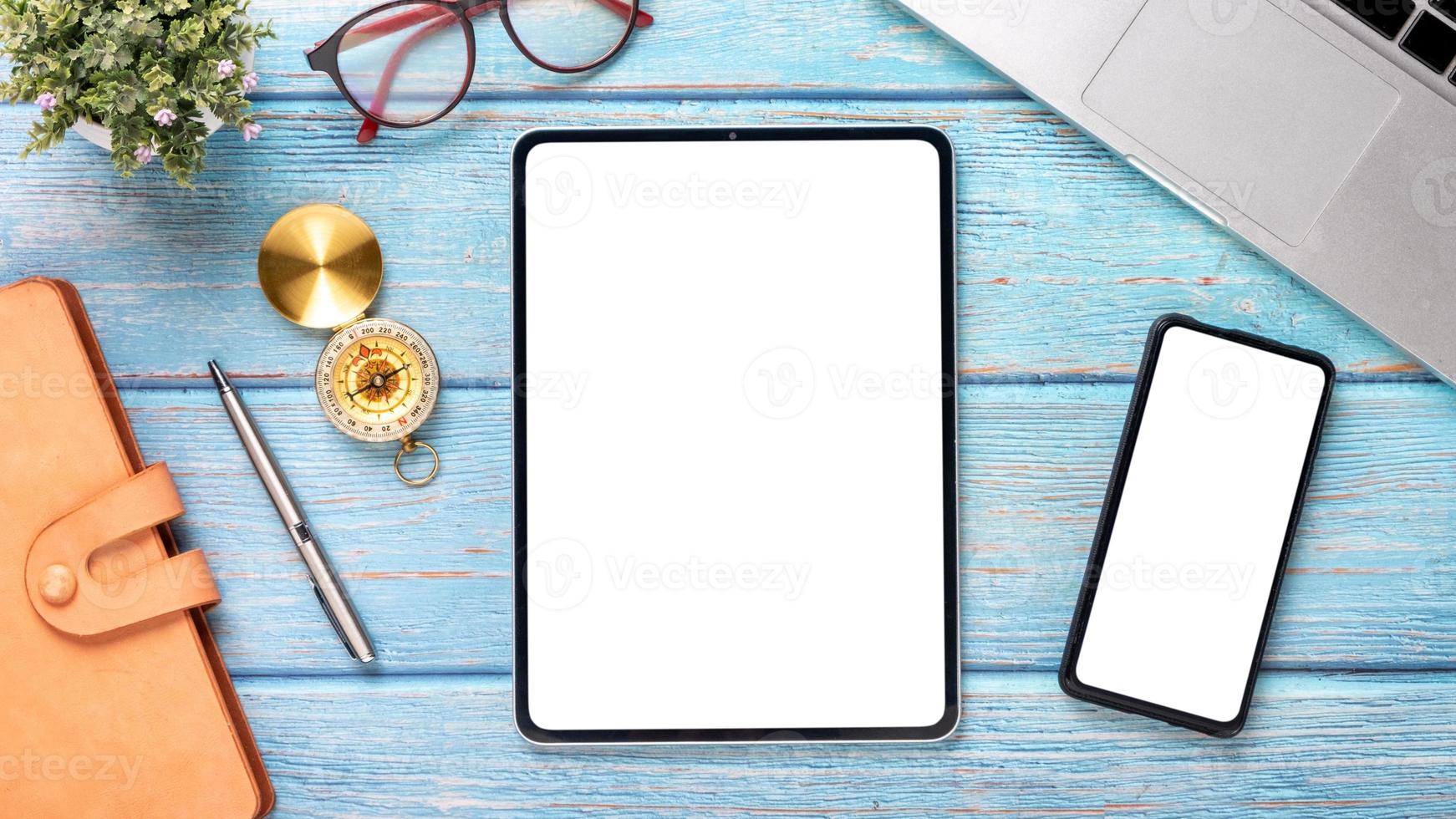 en bois bureau lieu de travail avec Vide écran tablette et téléphone intelligent, ordinateur portable, carnet de notes, stylo et monocle, Haut vue plat allonger avec copie espace. photo