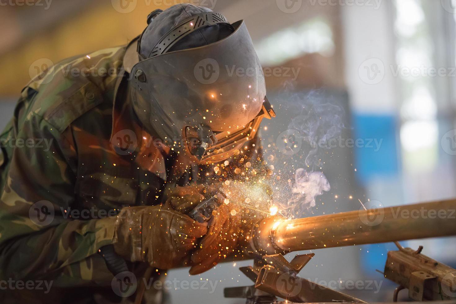 soudeur à travail. homme dans une protecteur masque. le soudeur fait du coutures sur le métal. des étincelles et fumée lorsque soudage. photo