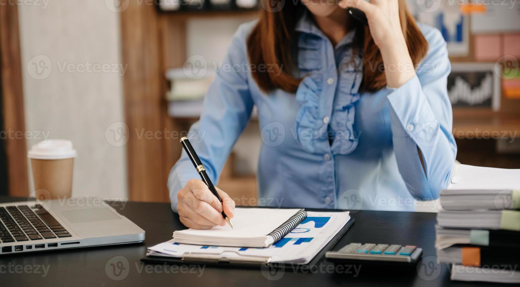 femme d'affaires a la joie de parler sur le smartphone et d'écrire sur le bloc-notes dans un bureau moderne photo