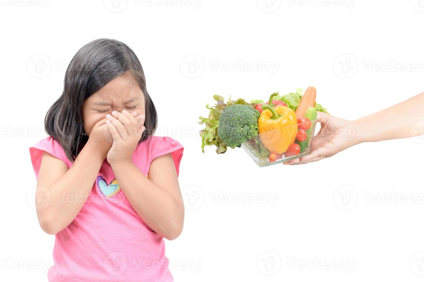 fille avec expression de dégoûter contre des légumes photo