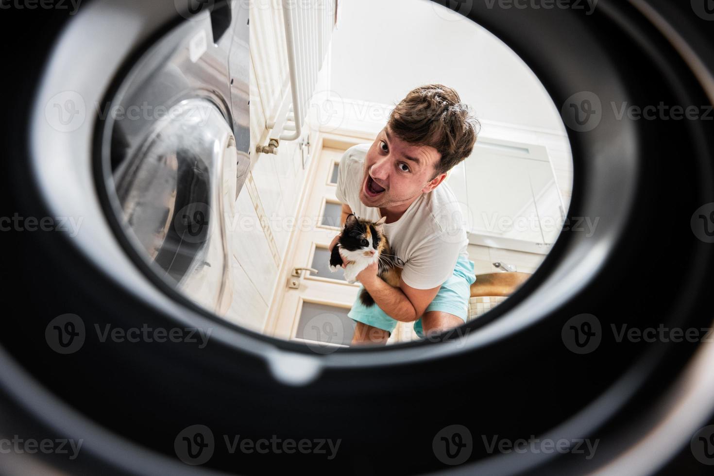 homme avec chat vue de la lessive machine à l'intérieur. Masculin Est-ce que blanchisserie du quotidien routine. photo