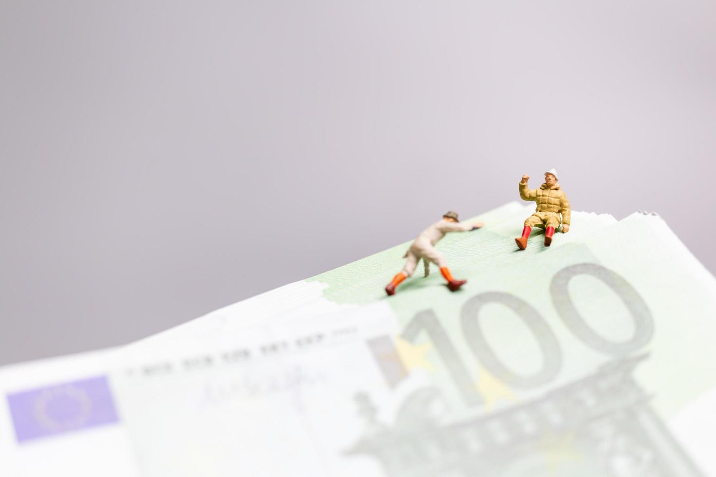 personnes miniatures, grimpeur grimpe sur un billet en euros, concept d'entreprise. photo