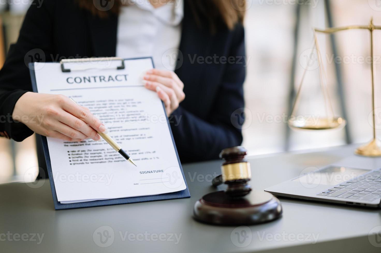 concept de justice et de droit. juge masculin dans une salle d'audience le marteau, travaillant avec un téléphone intelligent et un ordinateur portable et une tablette numérique sur une table en bois à la lumière du matin photo