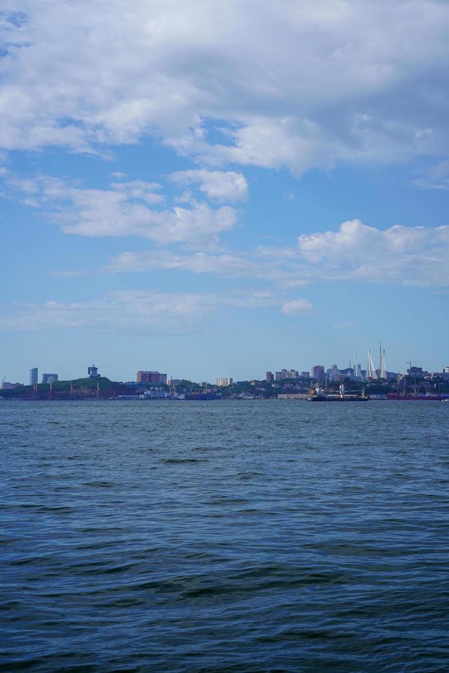 Ciel bleu nuageux sur un plan d'eau et ville sur un rivage photo