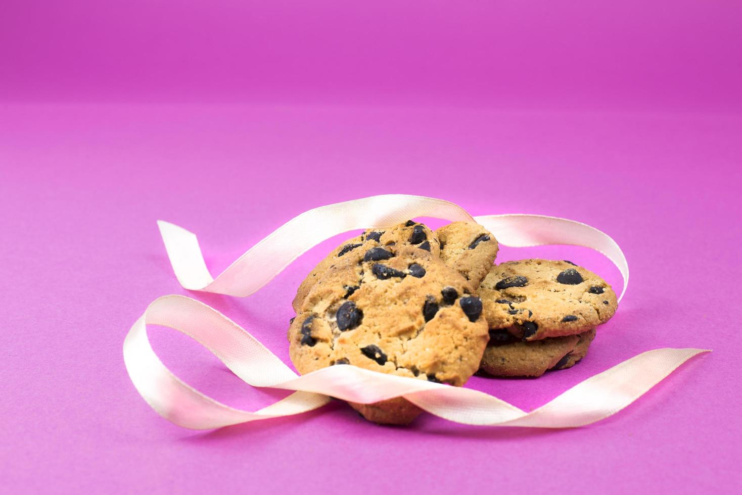 cinq biscuits avec Chocolat gouttes et blanc ruban sur rose Contexte photo