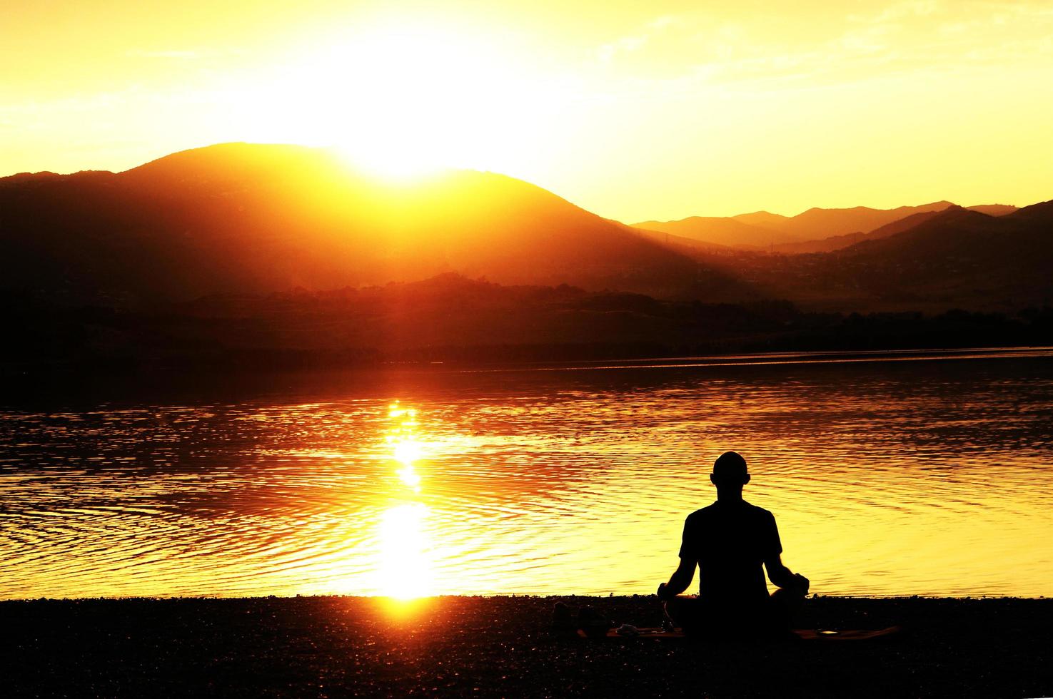 silhouette d'un homme méditant au bord d'un lac photo