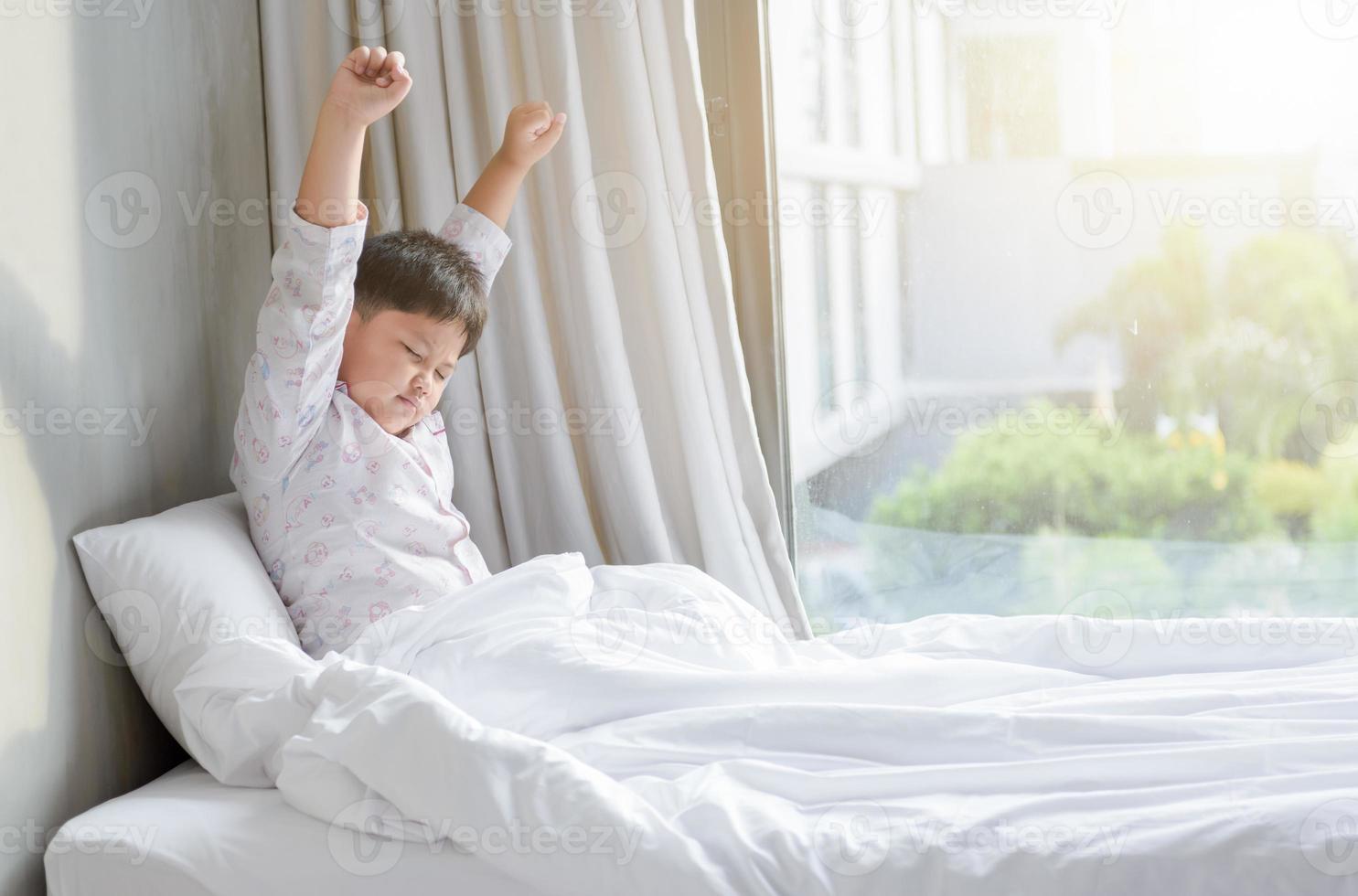 obèse graisse garçon dans pyjamas est séance sur lit photo