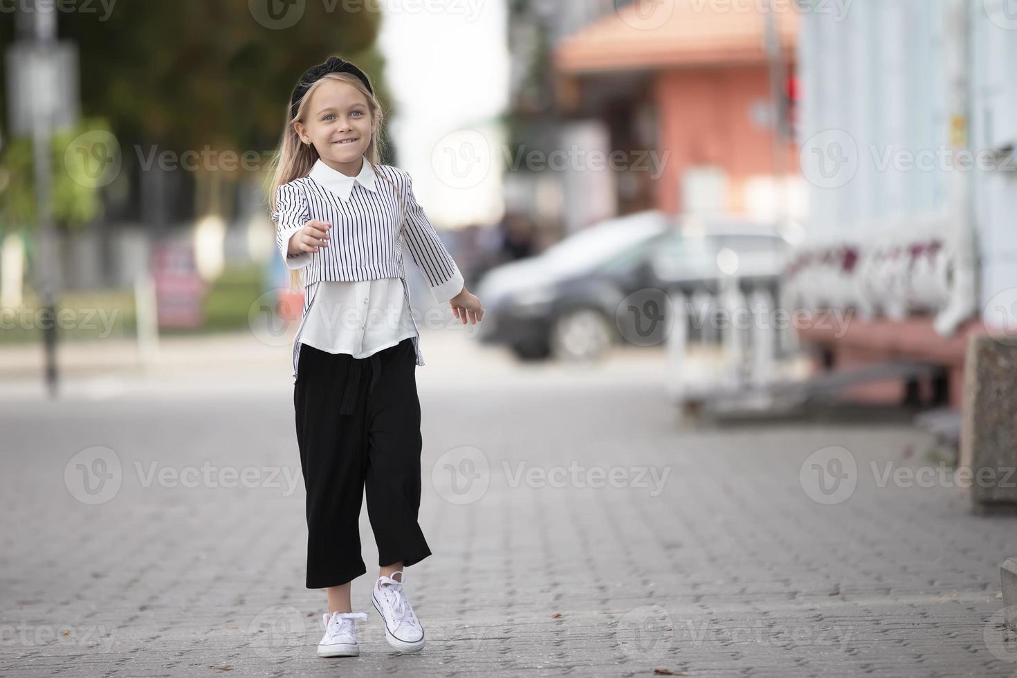 joyeux peu fille sur le rue de le ville. une enfant dans un Urbain paramètre. photo