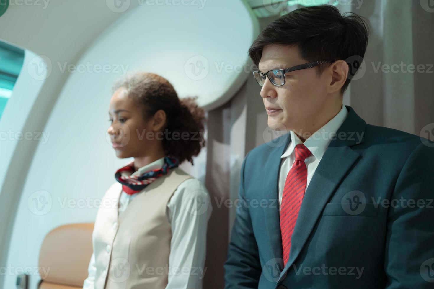 vol préposé saluer les passagers comme elles ou ils entrer le avion à Localiser une siège dans le cabine. photo