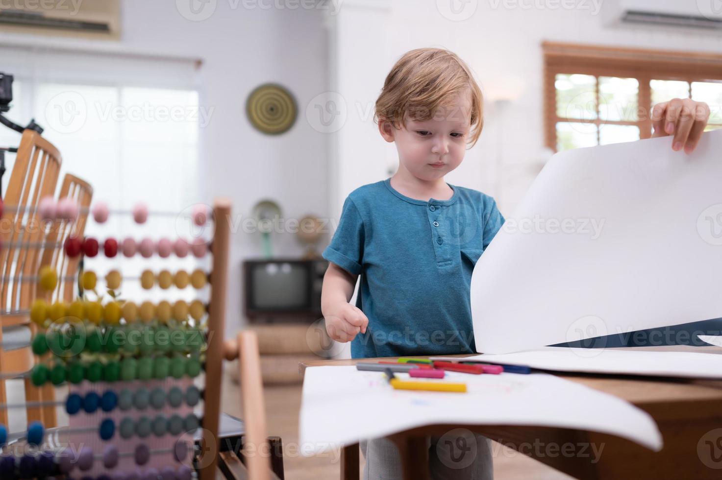 une peu enfant imagination est représentée par coloré crayon dessins, avec le mère attentivement surveillance dans le vivant pièce de le maison. photo