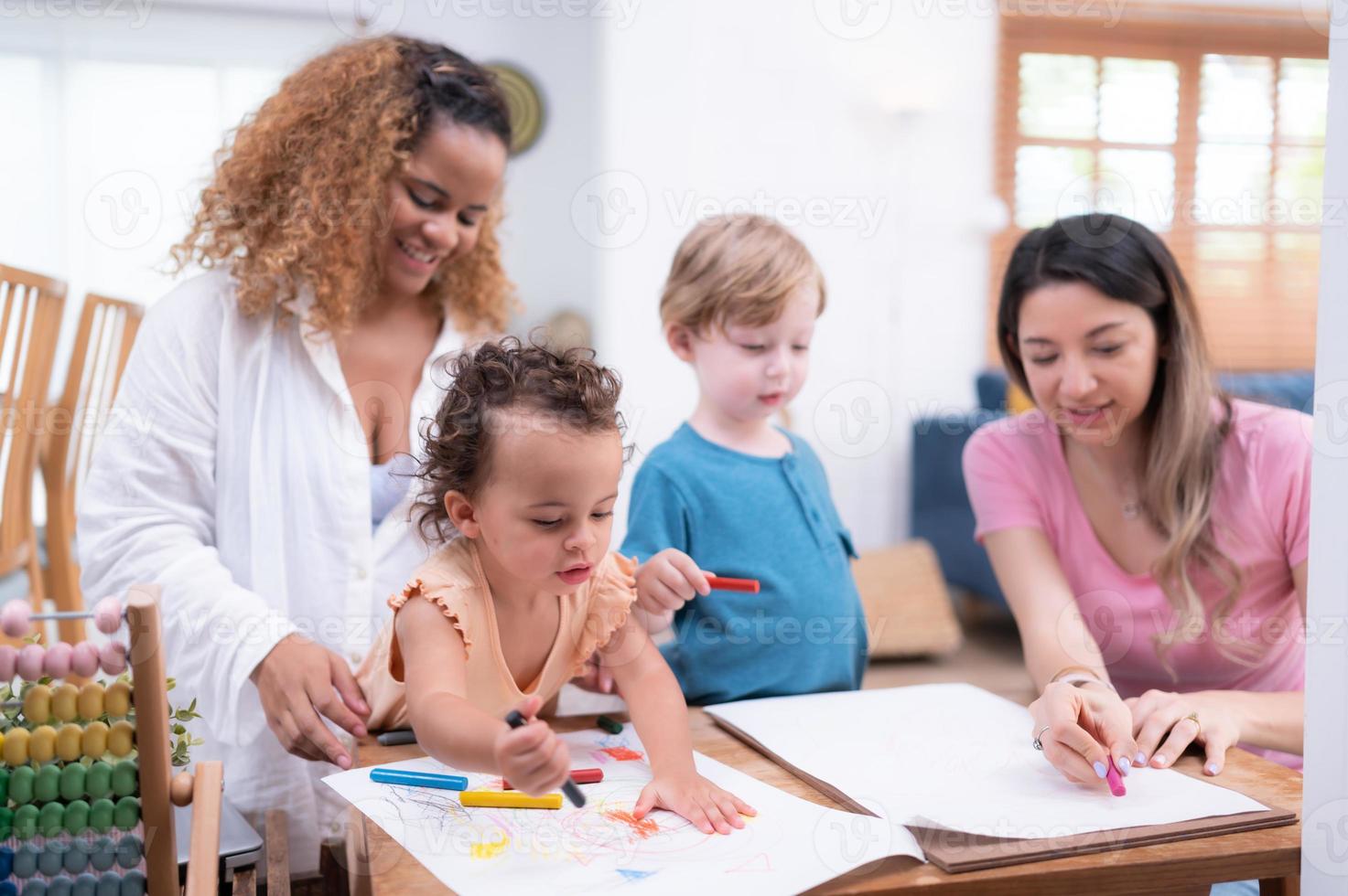 une peu enfant imagination est représentée par coloré crayon dessins, avec le mère attentivement surveillance dans le vivant pièce de le maison. photo